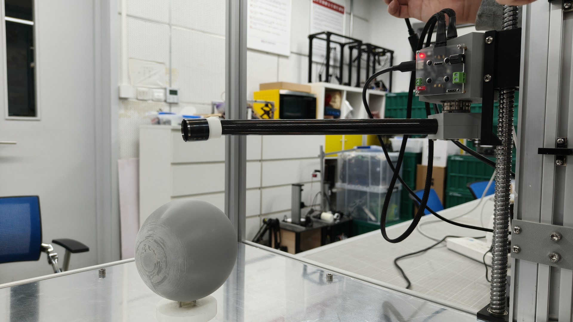 Side view of the physical peeling prototype with the rotating arm aligned to a spherical test fixture