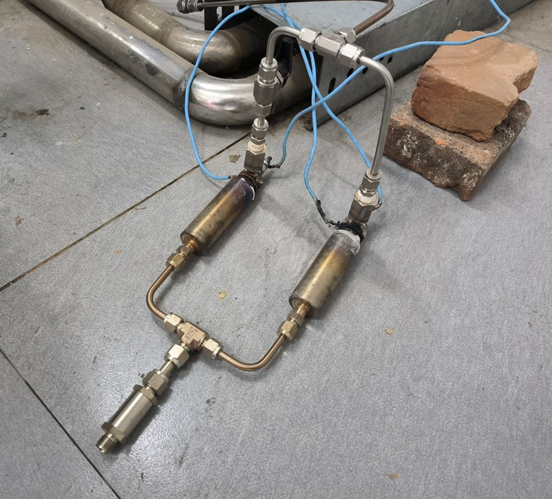 Physical ammonia cracker hardware with connected gas lines on the laboratory floor