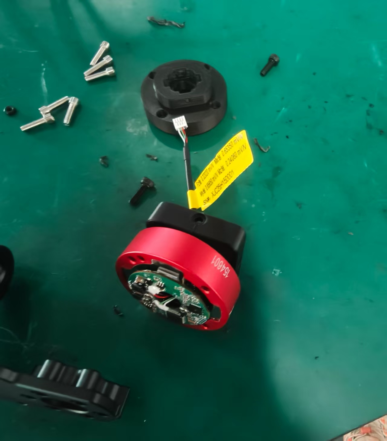 Physical six-axis wrist force sensor with its mounting flange, electronics, cable, and mating hardware visible on the assembly bench